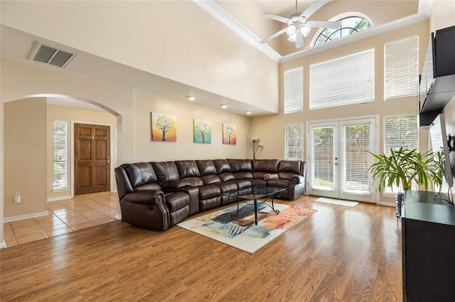living area featuring french doors, light wood-style flooring, a ceiling fan, visible vents, and arched walkways