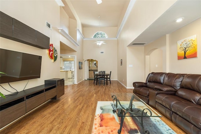 living area with visible vents, ceiling fan, light wood finished floors, and arched walkways