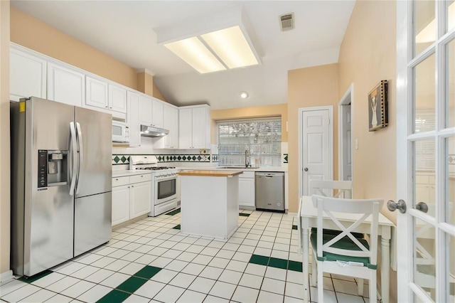 kitchen with appliances with stainless steel finishes, lofted ceiling, white cabinets, and under cabinet range hood