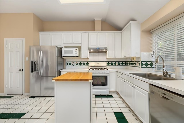 kitchen with under cabinet range hood, light tile patterned flooring, a sink, stainless steel appliances, and wood counters