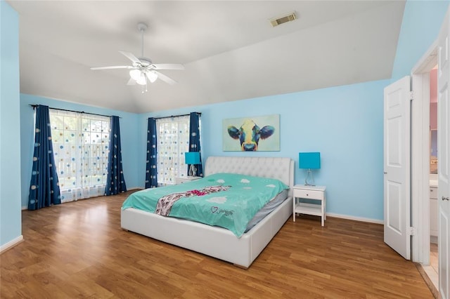 bedroom featuring visible vents, baseboards, vaulted ceiling, and wood finished floors