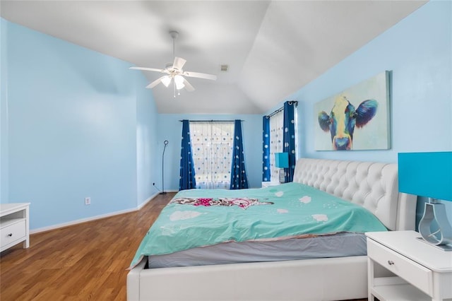 bedroom with baseboards, vaulted ceiling, a ceiling fan, visible vents, and wood finished floors