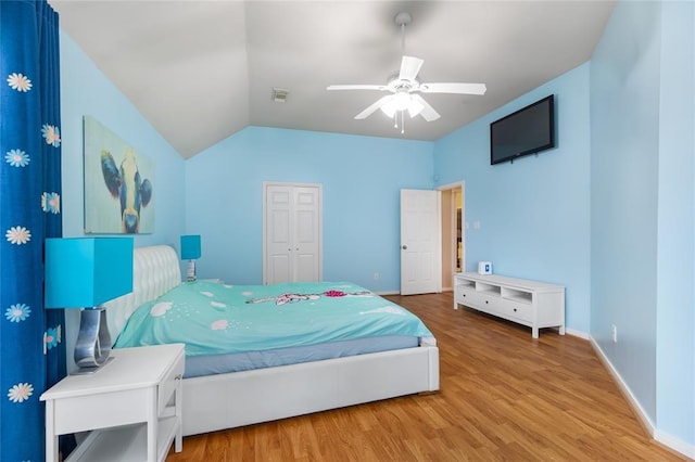 bedroom with baseboards, vaulted ceiling, a ceiling fan, visible vents, and wood finished floors