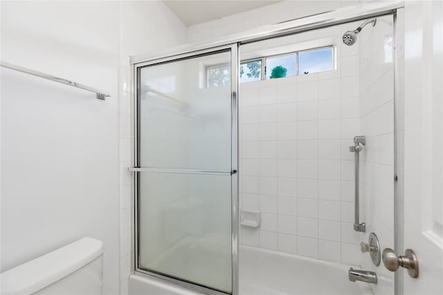 bathroom featuring enclosed tub / shower combo and toilet
