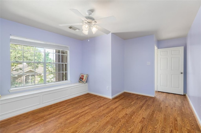 spare room featuring visible vents, ceiling fan, wood finished floors, and baseboards