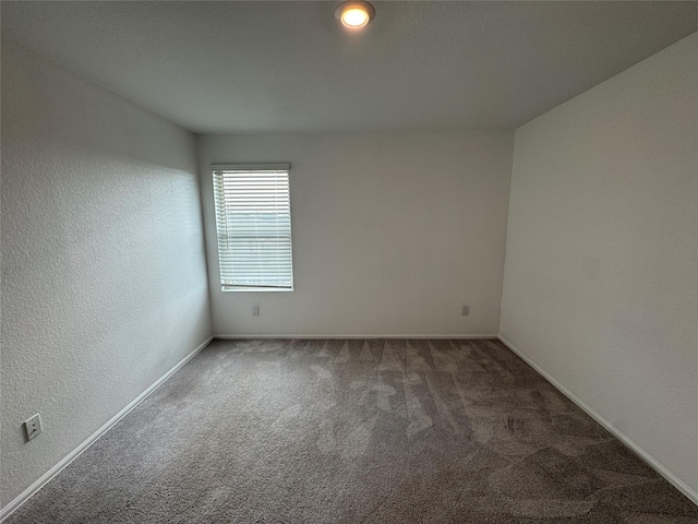 carpeted spare room with baseboards and a textured wall