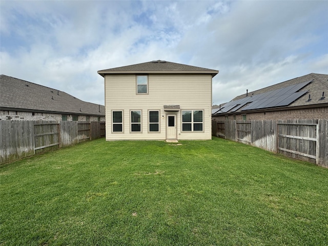 rear view of house with a lawn and a fenced backyard