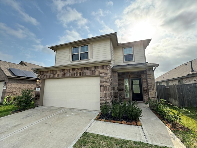 view of front of property featuring brick siding, fence, driveway, and a garage