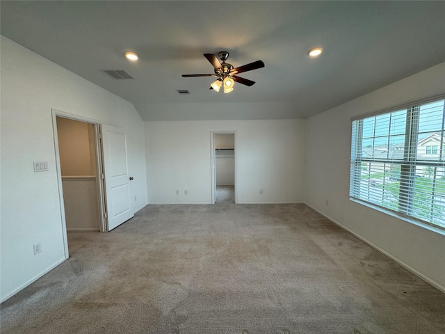 unfurnished bedroom featuring a walk in closet, visible vents, and light carpet