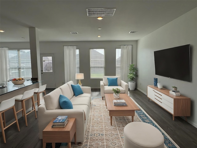 living room with wood finished floors, visible vents, and baseboards