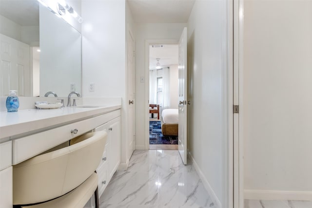 bathroom with marble finish floor, ensuite bath, vanity, and baseboards