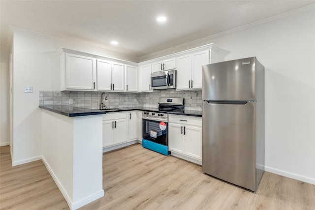 kitchen featuring stainless steel appliances, white cabinets, a sink, and crown molding