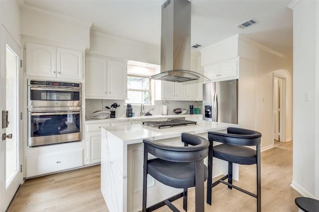 kitchen with white cabinetry, ornamental molding, visible vents, appliances with stainless steel finishes, and island range hood