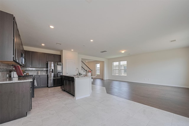 25327 Cheshire Knoll St, Katy, TX 77493 - kitchen featuring fridge with ice dispenser, open floor plan, decorative backsplash, dark brown cabinetry, and light tile patterned floors