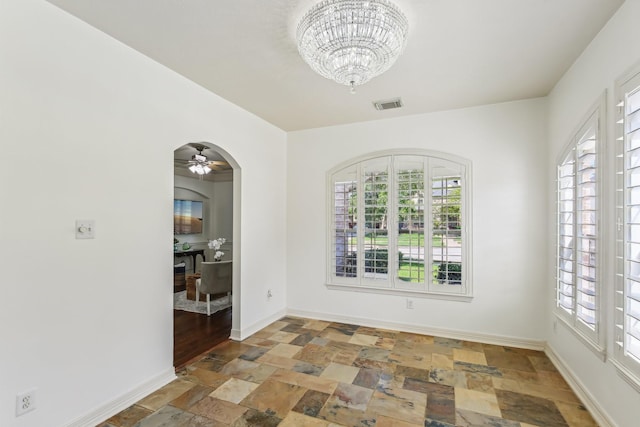 15614 Stone Gables Ln, Houston, TX 77044 - spare room featuring stone tile flooring, a chandelier, baseboards, arched walkways, and ceiling fan