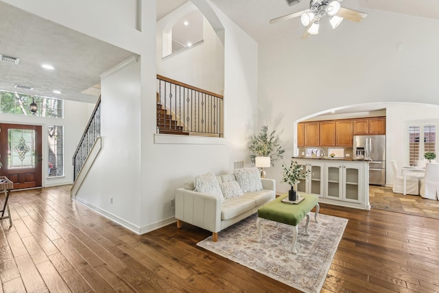 15614 Stone Gables Ln, Houston, TX 77044 - living room with stairs, arched walkways, a high ceiling, dark wood-style flooring, and ceiling fan