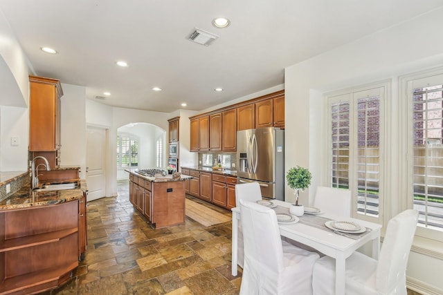 15614 Stone Gables Ln, Houston, TX 77044 - kitchen featuring appliances with stainless steel finishes, arched walkways, a sink, a kitchen island, and recessed lighting