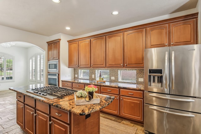 15614 Stone Gables Ln, Houston, TX 77044 - kitchen with appliances with stainless steel finishes, arched walkways, stone tile floors, a center island, and stone countertops