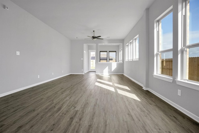 unfurnished living room with a ceiling fan, baseboards, and dark wood-style flooring