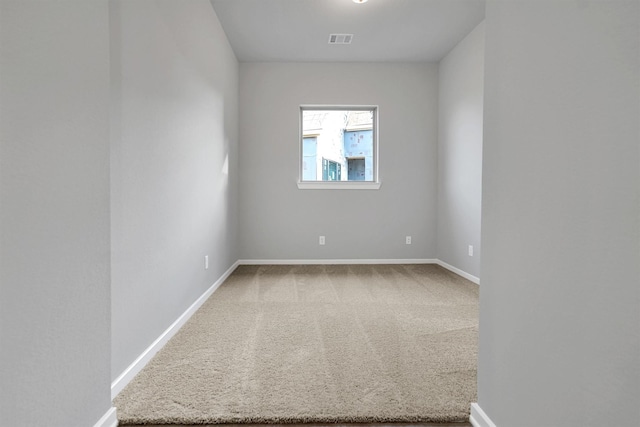 carpeted spare room with visible vents and baseboards