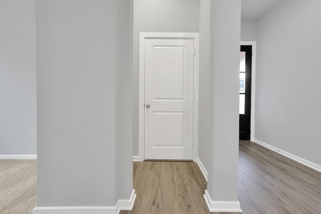 corridor with baseboards and light wood-style flooring