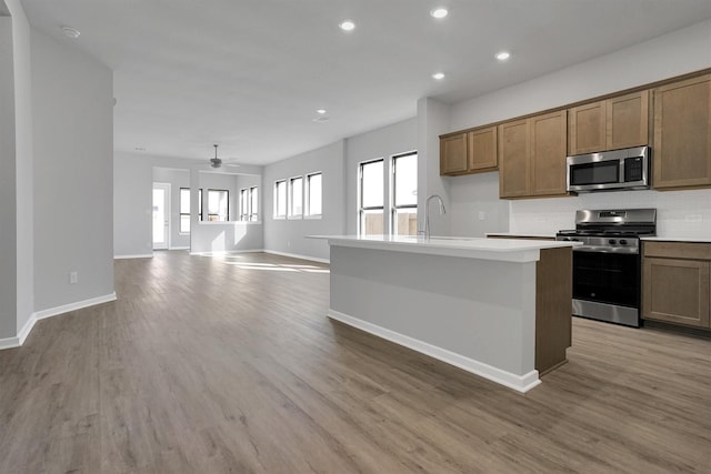 kitchen with backsplash, a ceiling fan, a sink, baseboards, and appliances with stainless steel finishes