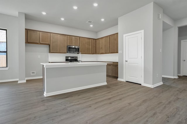 kitchen with light wood-style flooring, visible vents, brown cabinetry, and stainless steel appliances