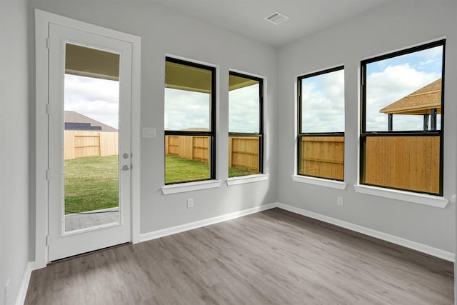 doorway to outside featuring visible vents, baseboards, wood finished floors, and a wealth of natural light