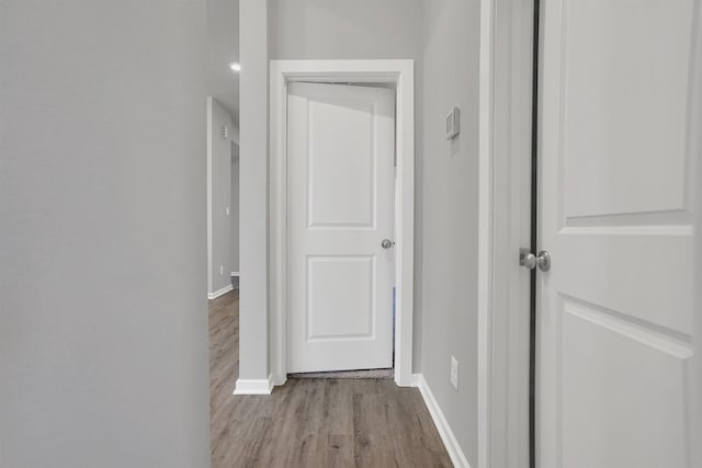 corridor featuring baseboards and wood finished floors