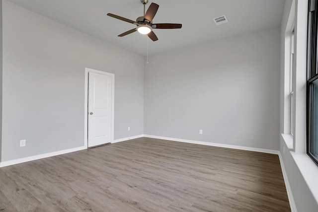 empty room with ceiling fan, baseboards, wood finished floors, and visible vents