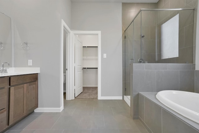 full bathroom featuring a shower stall, a bath, vanity, baseboards, and tile patterned flooring