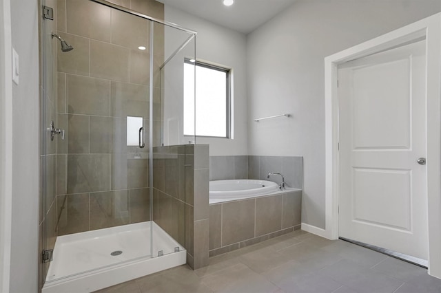 bathroom with a bath, a shower stall, tile patterned flooring, and baseboards