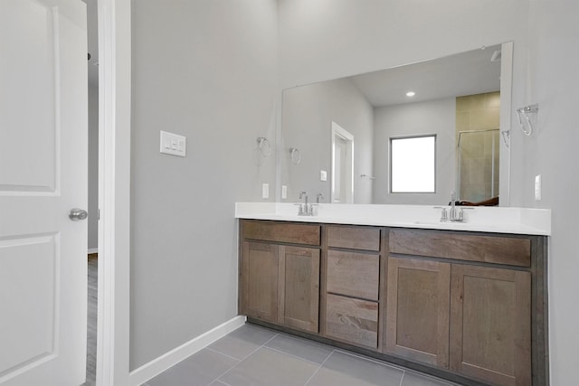 full bath with baseboards, a sink, double vanity, and a tile shower