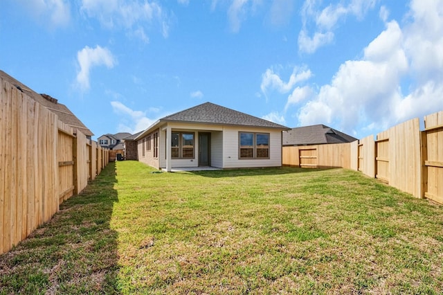 back of house featuring a yard, a shingled roof, and a fenced backyard