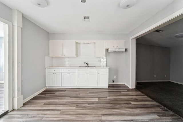 5910 Edward Dr, Houston, TX 77396 - kitchen with white cabinets, baseboards, a sink, wood finished floors, and decorative backsplash