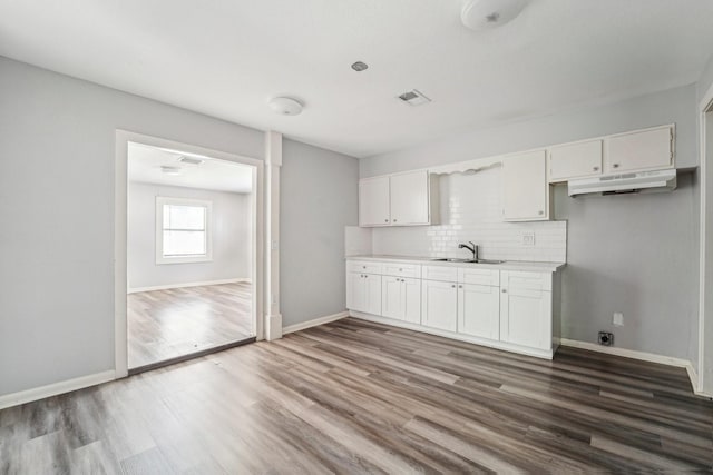 5910 Edward Dr, Houston, TX 77396 - kitchen featuring tasteful backsplash, white cabinets, under cabinet range hood, wood finished floors, and baseboards