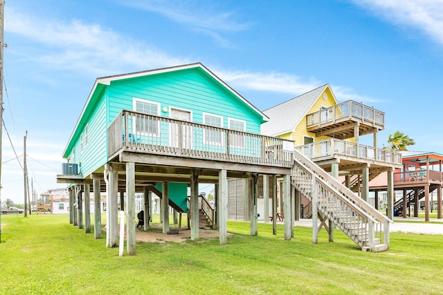 rear view of house with central air condition unit, a carport, stairs, and a lawn