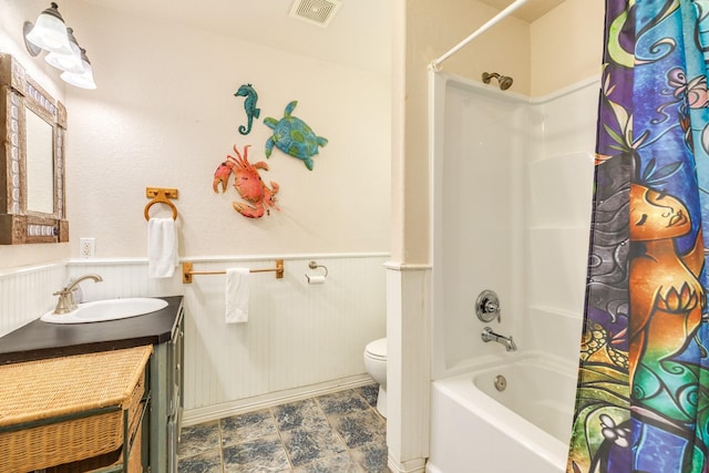 bathroom with toilet, vanity, wainscoting, and visible vents