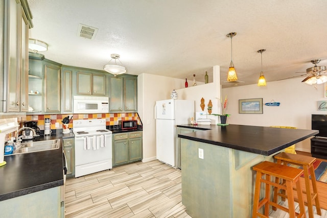 kitchen featuring ceiling fan, white appliances, visible vents, a sink, and dark countertops