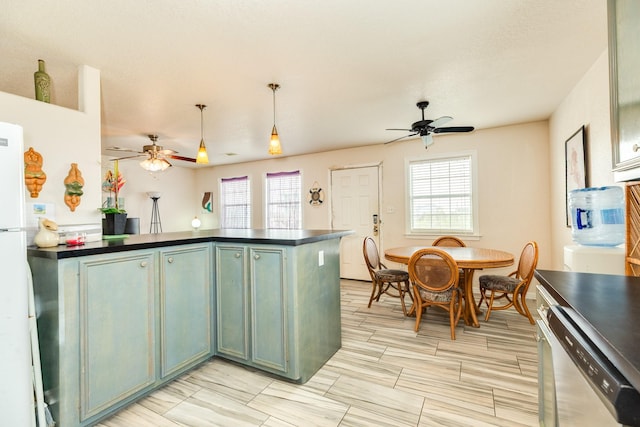 kitchen with dark countertops, freestanding refrigerator, a ceiling fan, and dishwasher