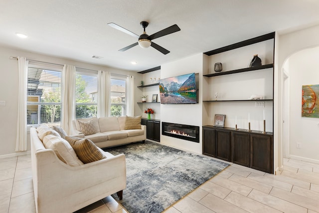 12420 Southern Trail Ct, Magnolia, TX 77354 - living room with visible vents, baseboards, a ceiling fan, light tile patterned flooring, and a glass covered fireplace