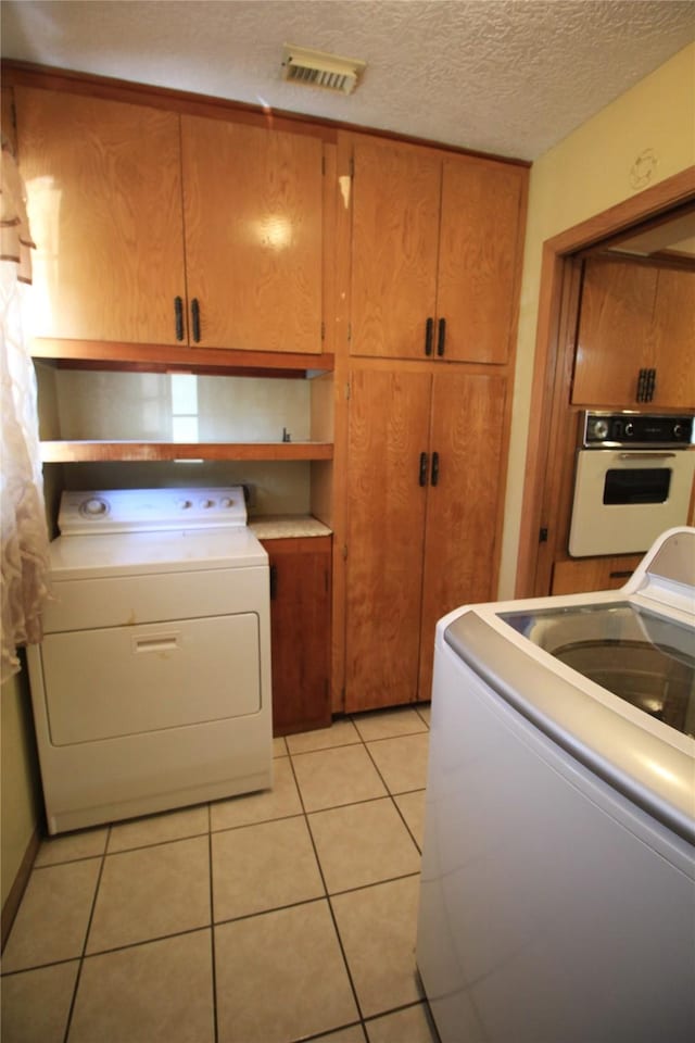 washroom with washer / dryer, cabinet space, visible vents, and light tile patterned floors