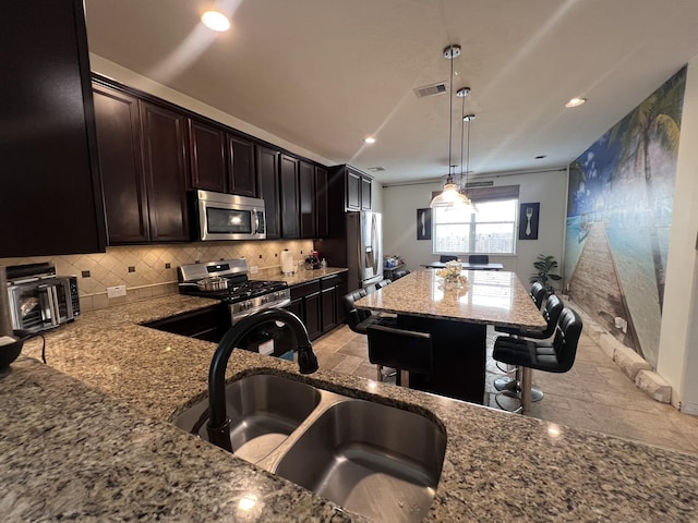 kitchen featuring visible vents, light stone countertops, a sink, appliances with stainless steel finishes, and backsplash