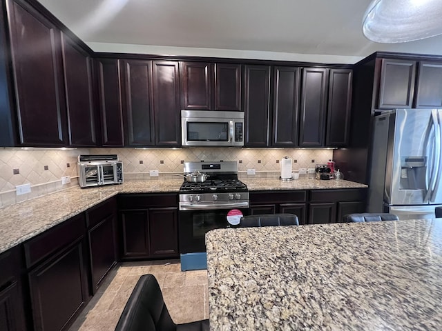 kitchen featuring decorative backsplash, light stone countertops, and stainless steel appliances
