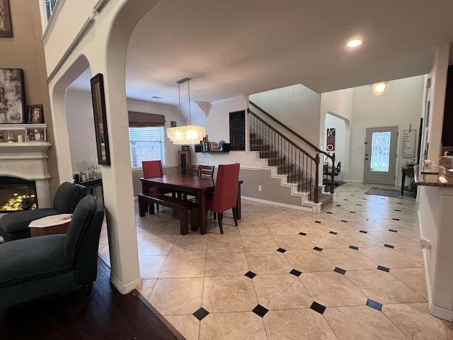 dining room with a chandelier, recessed lighting, baseboards, a lit fireplace, and stairway