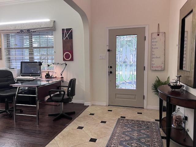 foyer featuring tile patterned floors, baseboards, arched walkways, and a wealth of natural light