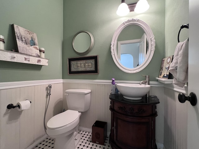 half bath featuring vanity, wainscoting, and toilet