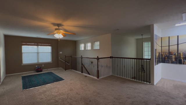 empty room with carpet floors, a ceiling fan, and baseboards