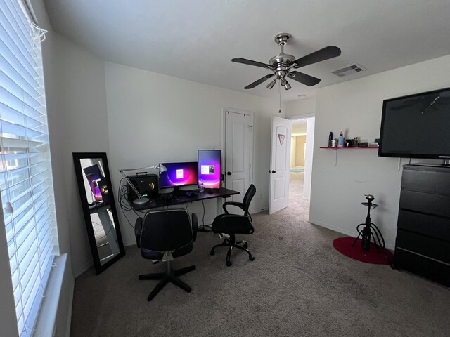 carpeted office space featuring baseboards, ceiling fan, and visible vents