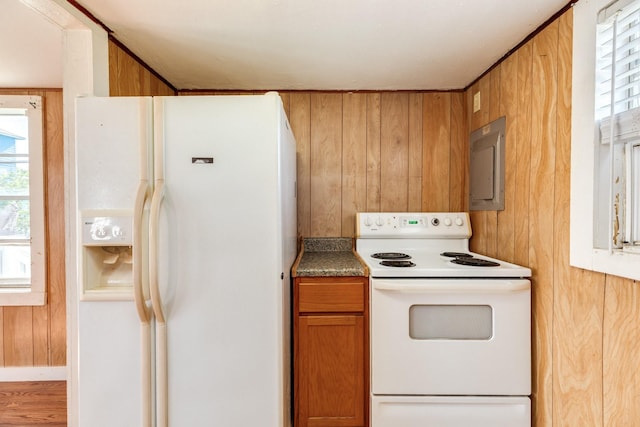 11213 Schwartz Dr, Galveston, TX 77554 - kitchen featuring wooden walls, white appliances, electric panel, and brown cabinets